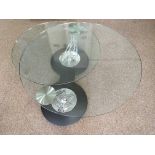 A glass swivel topped table on chrome and black base.