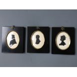 Three black framed, signed, silhouette portraits.