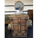 An oak two door cabinet with a magony oval shaped mirror.