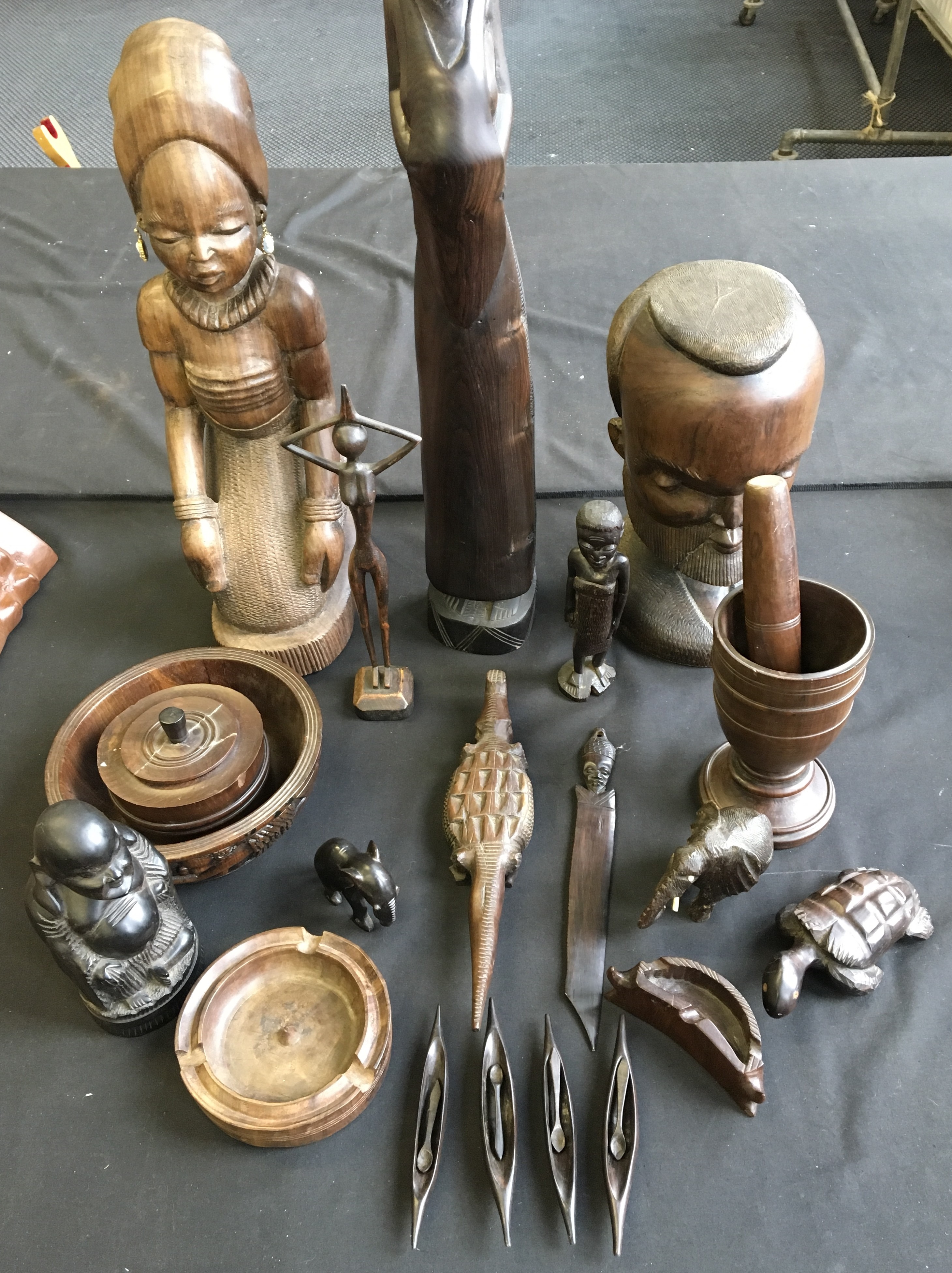 A selection of carved wooden items including African sculptures, salt dishes with spoons, pestle and