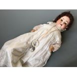 A Heubach Koppelsdorf 320 6 1/2 Germany doll with bisque head in christening dress with rattle.