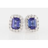 A pair of 18ct white gold tanzanite and diamond cluster stud earrings, each set with an emerald