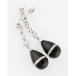 A pair of onyx and diamond drop stud earrings, each with a pear shaped onyx dropper inlaid with