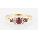 A ruby and diamond ring, set with three graduated round cut rubies, with four eight-cut diamond