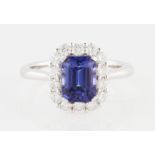 An 18ct white gold tanzanite and diamond cluster ring, set with a central emerald cut tanzanite,