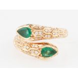 An 18ct rose gold emerald and diamond snake design ring, the cross over design set with an emerald