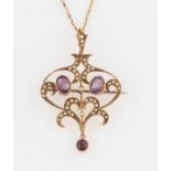 An early 20th Century amethyst and seed pearl pendant / brooch, the open metalwork design set with