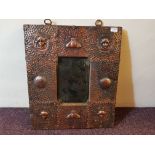 An Arts and Craft copper framed wall mirror decorated in each corner by masks, overall size 62cm x