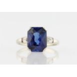 A synthetic sapphire and colourless paste ring, set with an emerald-cut synthetic sapphire,