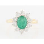 An 18ct yellow gold emerald and diamond cluster ring, set with an oval cut emerald measuring approx.