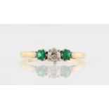 An emerald and diamond three stone ring, set with a central old cut diamond, measuring approx. 0.