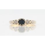 An 18ct yellow gold sapphire and diamond ring, set with a central square cut sapphire, flanked to