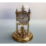 A brass anniversary mantle clock under glass dome.