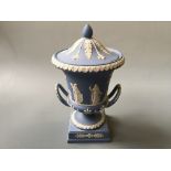 A Wedgwood pale blue two handled urn with lid, Grecian scene with trees, height 30cm.