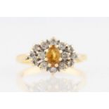 An 18ct yellow gold orange sapphire and diamond cluster ring, set with a central orange sapphire,