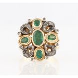 An emerald and diamond dress ring, set with five oval cut emeralds, surrounded by open metalwork set