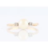 A 9ct yellow gold pearl and diamond three stone ring, set with a central pearl flanked to either