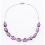 An amethyst collar, set with ten oval cut amethysts to a belcher link chain, set in unmarked white