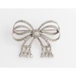 A Belle Epoque style diamond bow design brooch, set with a central transitional cut diamond,