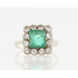 An emerald (possibly synthetic) and diamond cluster ring, set with a central square cut emerald (