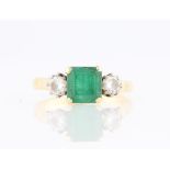 An emerald and diamond three stone ring, set with a central emerald cut emerald, measuring approx.