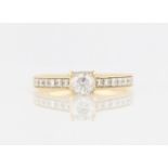 A diamond ring, set with a central round brilliant cut diamond, measuring approx. 0.40ct, flanked to