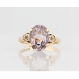 A hallmarked 9ct yellow gold amethyst ring, set with an oval cut amethyst flanked to either side