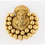 A yellow metal Indian style brooch, featuring a central deity surrounded by spheres design,
