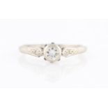 A diamond ring, set with a central round brilliant cut diamond, measuring approx. 0.25ct, flanked to