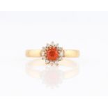 A fire opal and diamond cluster ring, set with a round cut fire opal surrounded by eight-cut