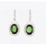 A pair of 18ct white gold green tourmaline and diamond drop earrings, each set with an oval cut