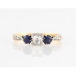 A sapphire and diamond three stone ring, set with a central transitional cut diamond, measuring