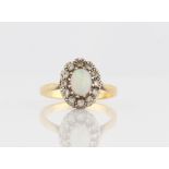 An opal and diamond cluster ring, set with an oval opal cabochon, measuring approx. 7x5mm,