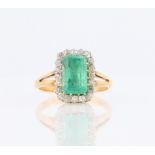 An emerald and diamond cluster ring, set with a central emerald cut emerald, measuring approx.