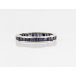 A sapphire full eternity ring, channel set with square cut sapphires in unmarked white metal, ring