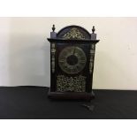A mahogany mantle clock with brass face and decoration and Roman numerals to face