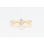 A hallmarked 9ct yellow gold diamond solitaire ring, bezel set with a round brilliant cut diamond,