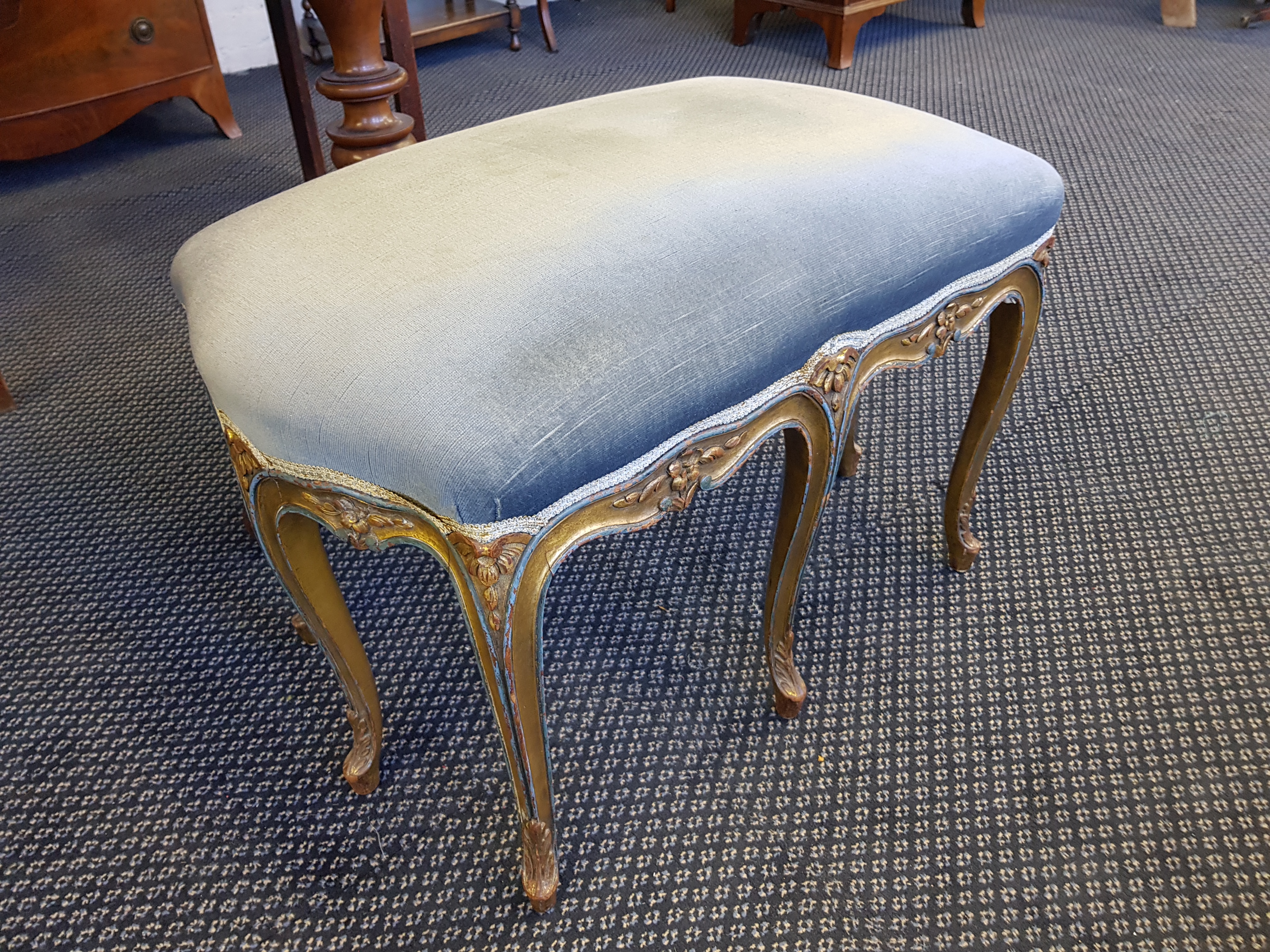 A French late 19th century eight legged stool gilt with dusty blue upholstery.