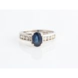 A sapphire and diamond ring, set with an oval cut sapphire, measuring approx. 7x5mm, with each