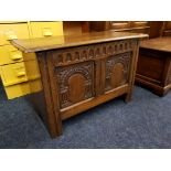 A reproduction distressed oak blanket chest with carved panel front.