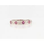 A hallmarked 18ct white gold ruby and diamond half eternity ring, set with four round cut rubies and