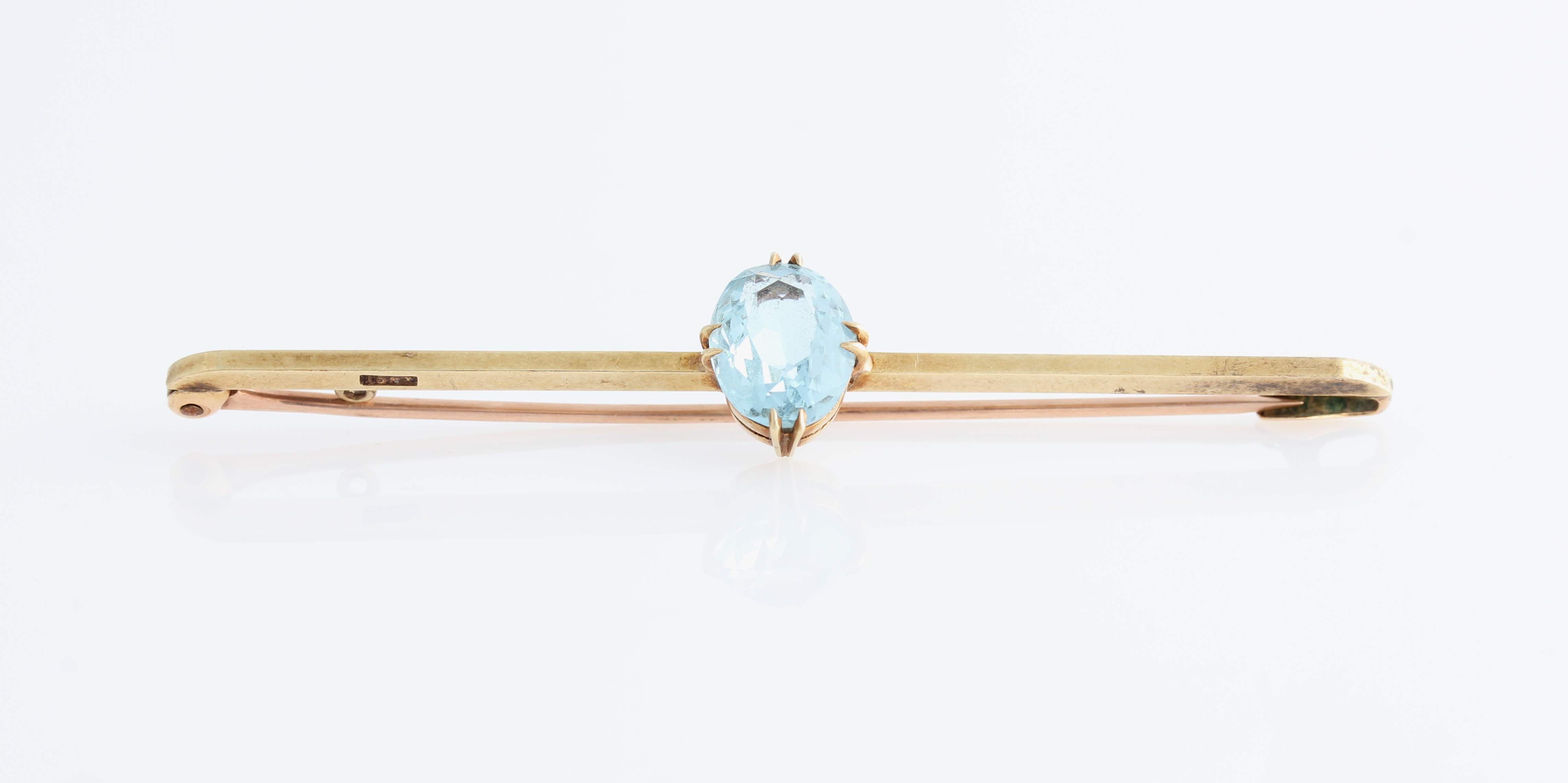 An aquamarine bar brooch, set with an oval cut aquamarine, measuring approx. 10x7mm, stamped 15ct,