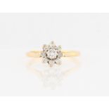 An 18ct yellow gold diamond flower design ring, set with a central round brilliant cut diamond