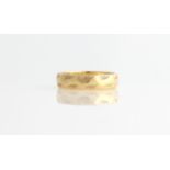 A hallmarked 18ct yellow gold wedding band with engraved leaf design.