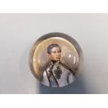 A Victorian glass paper weight depicting man in uniform.