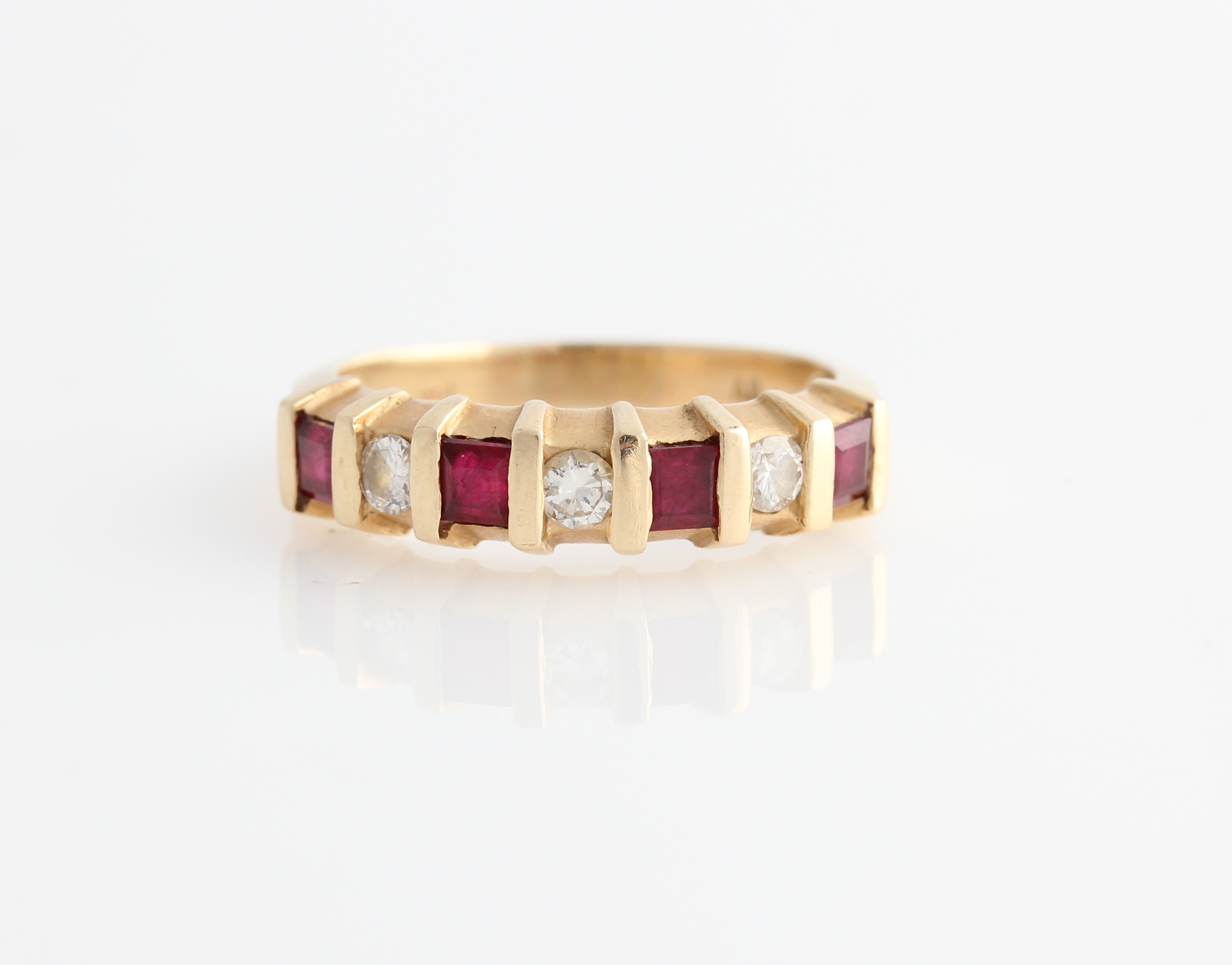 A ruby and diamond seven stone ring, bar set alternately with four square cut rubies and three round