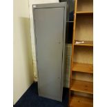 A grey metal single door gun cabinet with keys.