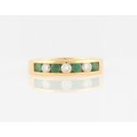 A hallmarked 18ct yellow gold emerald and diamond half eternity ring, channel set with four round