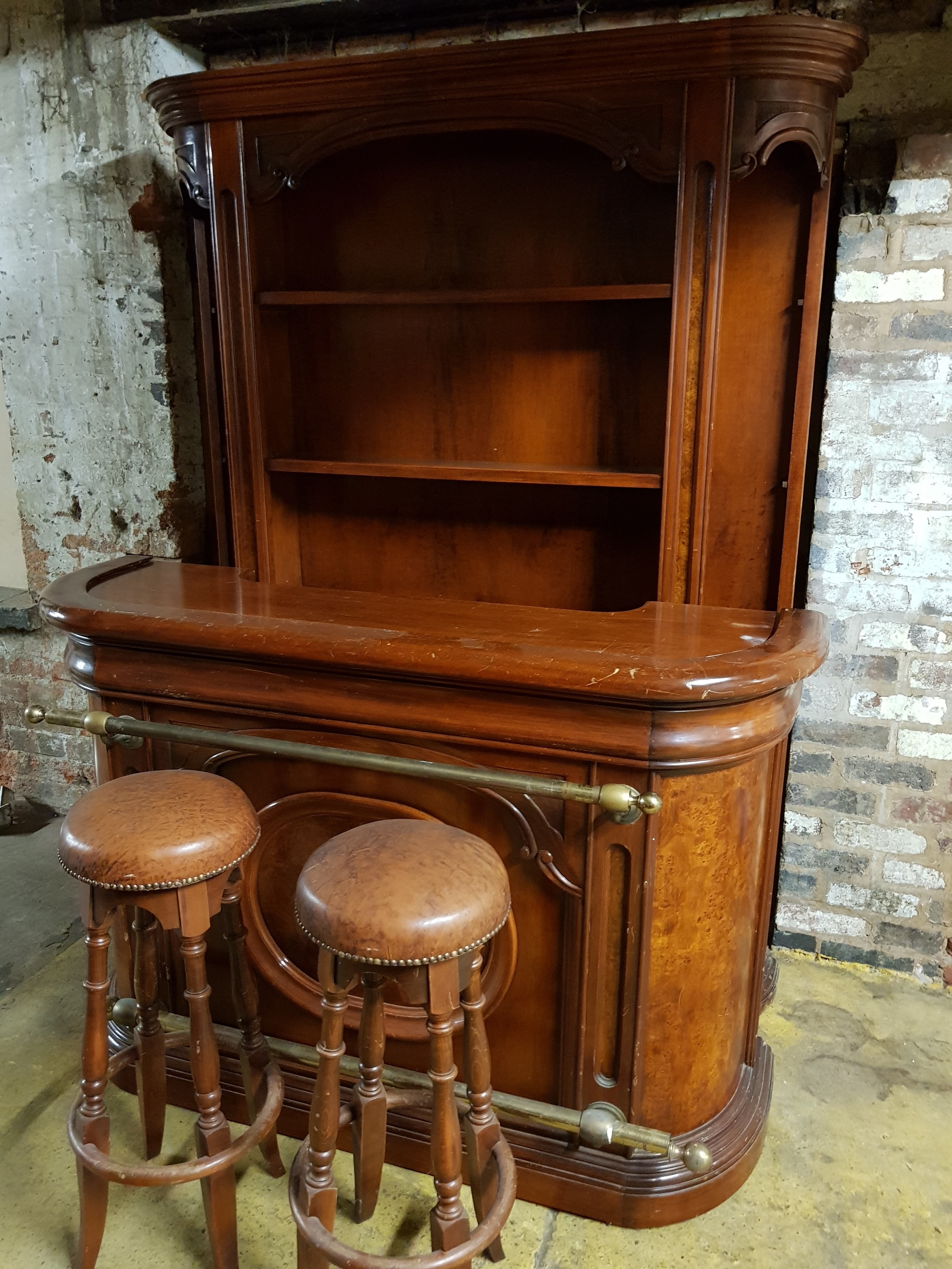 A mahogany bar with built in fridge, large shelf back and two bar stools.