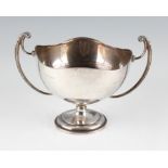 A silver twin handled trophy, with waved rim and scroll handles, raised on stepped circular foot,